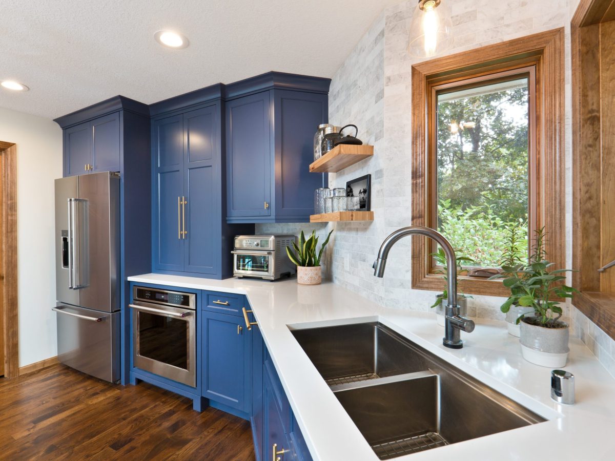 A contemporary kitchen renovation remodeling featuring a hardwood floor  kitchen sink, appliances and quartz counter top.